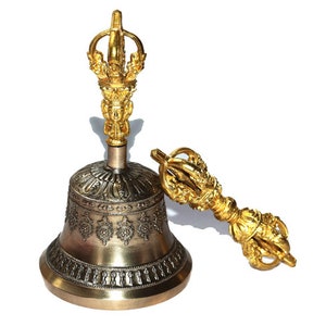 May include: A gold and silver Tibetan singing bowl with a matching hand-held striker. The bowl has intricate designs and the striker has a decorative handle.