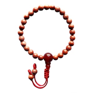 May include: A brown beaded bracelet with a red gemstone bead and red string tassel.