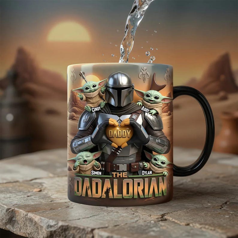Puede incluir: Taza de cer&aacute;mica con un dise&ntilde;o de The Mandalorian sosteniendo un objeto en forma de coraz&oacute;n con la palabra "DADDY". La taza tambi&eacute;n presenta a Grogu y el texto "THE DADALORIAN" y los nombres "Cindy", "Abby", "Simon" y "Dylan". La taza tiene un asa negra.