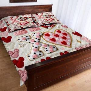 Puede incluir: Un edred&oacute;n acolchado y dos fundas de almohada con un dise&ntilde;o de coraz&oacute;n y Minnie Mouse. El edred&oacute;n tiene un fondo crema con corazones rojos, lazos rosas y la letra "I" con lunares negros. Las fundas de almohada tienen un dise&ntilde;o similar.