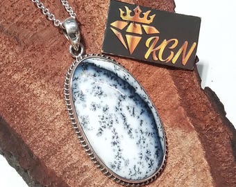 May include: A silver chain necklace with a pendant featuring a white and black dendritic agate stone set in a silver oval frame. The stone has a natural, organic pattern.