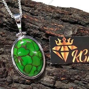 Puede incluir: Un collar con un colgante de plata con una piedra ovalada de turquesa verde. La piedra tiene un patr&oacute;n de m&aacute;rmol y est&aacute; engastada en un bisel de plata.