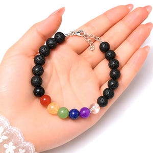 May include: A beaded bracelet featuring a series of black porous lava stone beads and a sequence of seven smooth, colorful gemstone beads in red, orange, green, blue, purple, and clear, finished with a silver-toned metal lobster clasp.