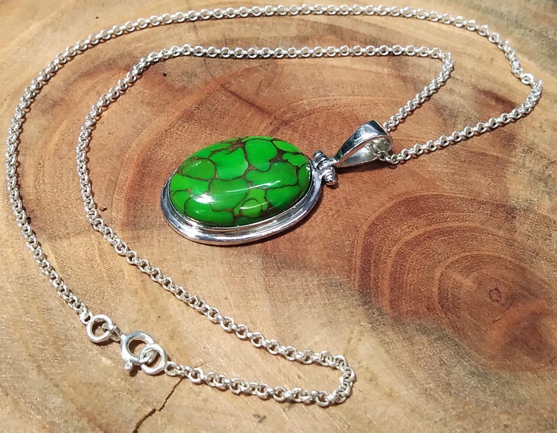Puede incluir: Un collar de cadena de plata con un colgante ovalado verde con una piedra turquesa. La piedra tiene un patr&oacute;n de m&aacute;rmol.