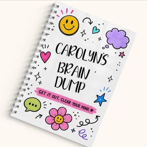 May include: A white spiral-bound notebook with the black text CAROLYN'S BRAIN DUMP and the phrase GET IT OUT. CLEAR YOUR MIND. on a pink banner. The cover features colourful doodles including a yellow smiley face, a pink flower, and stars.