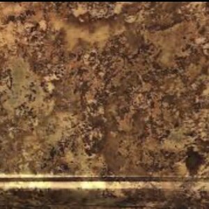 Op de afbeelding: Een rechthoekig oppervlak met een gevlekt, meerkleurig bruin en beige patroon met donkerbruine spikkels en aders. Een horizontale, verhoogde lineaire rand loopt over het onderste gedeelte van het beeld en vormt een duidelijke afscheiding.