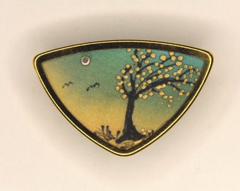 Two pretty brooches with gold colored rim, inside silk painted with small trees