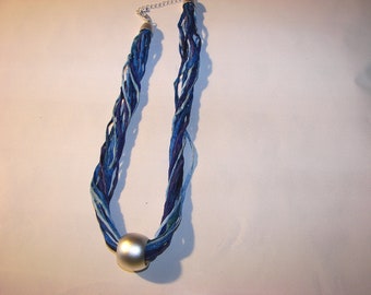 A beautiful necklace made of 12 individual silk cords in different shades of blue