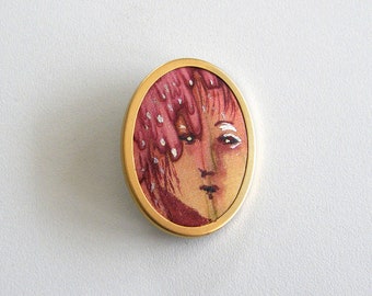 Two different brooches, silk inside, hand painted with a face.