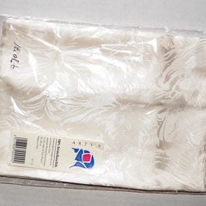 Könnte beinhalten: Ein weißer Seidenschal mit einem Blumenmuster. Der Schal ist in einer durchsichtigen Plastiktüte verpackt mit einem Etikett, auf dem "ARTY'S 100% Silk Satin" steht.