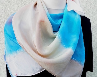 A flattering crepe de chine silk scarf, painted with French paint in light blue, beige, off-white, decorated with small white dots.