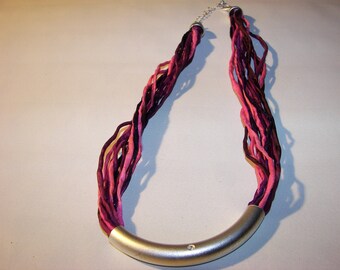 A beautiful necklace made of 12 individual silk cords in different shades of red