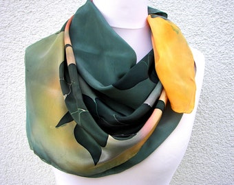 A beautiful shiny silk crepe de chine scarf hand painted in green, corn yellow and salmon with painted green fantasy leaves.