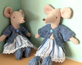 Könnte beinhalten: Zwei Plüschmausspielzeuge, die blaue gestrickte Strickjacken und gestreifte Röcke mit Spitzenbesatz tragen. Die Mäuse haben braune Augen und Nasen und sitzen auf einer hellgrünen Oberfläche.
