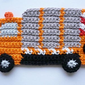 Könnte beinhalten: Ein handgehäkelter Lastwagen in Orange, Grau, Schwarz, Weiß und Gelb. Der Lastwagen hat schwarze Räder mit weißen Akzenten, einen grauen Körper und orangefarbene Details. Die Häkelarbeit ist detailliert und strukturiert.
