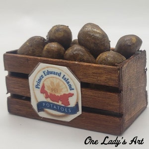 May include: A wooden crate filled with brown potatoes. The crate has a label that reads "Prince Edward Island PEI POTATOES".