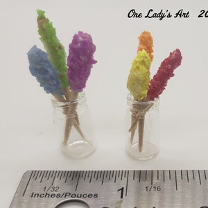 May include: Two glass jars filled with colorful candy sticks on wooden skewers. The jars are about 1 inch tall and are sitting on a ruler. The ruler is marked in inches and 1/16ths of an inch. The text "One Lady's Art 2020" is visible in the top right corner of the image.