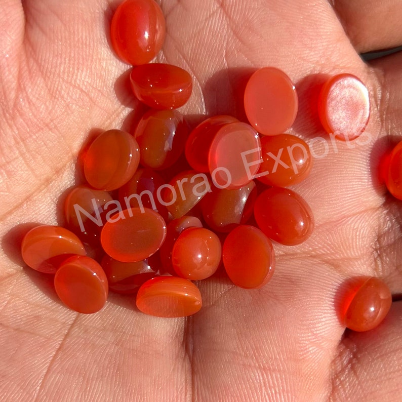 K&ouml;nnte beinhalten: Eine Sammlung von 20 ovalen Karneol-Edelsteinen. Die Steine sind tief orange-rot und haben eine glatte, polierte Oberfl&auml;che.