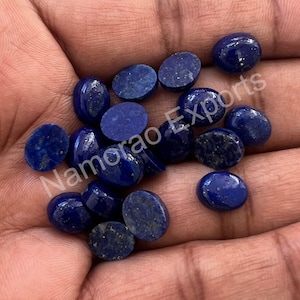 May include: A collection of 17 oval-shaped, blue lapis lazuli cabochons. The stones are smooth and polished, with a deep blue color and flecks of white and gold.