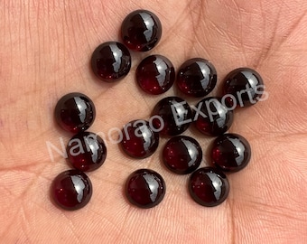 May include: A collection of 15 round, dark red gemstones. The gemstones are smooth and polished, and they have a glossy finish.