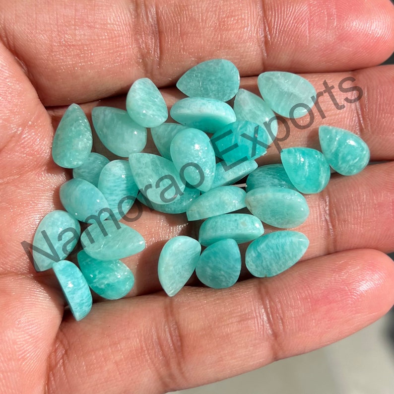 May include: A collection of light green, pear-shaped gemstones. The stones are smooth and polished, with a translucent appearance.