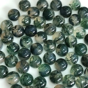 May include: A collection of polished, round gemstones with a moss agate appearance. The stones display a mix of translucent white, green, and gray colors, with intricate, natural patterns. The gemstones are suitable for jewelry making or crafting.
