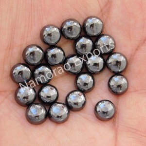 May include: A collection of 18 round, black hematite cabochons. The cabochons are smooth and have a slightly metallic sheen.