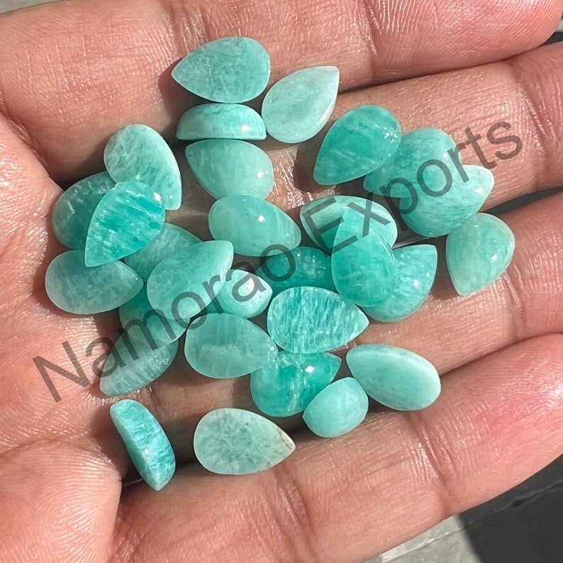 May include: A collection of green gemstone cabochons in a pear shape. The stones are smooth and polished, with a translucent appearance.