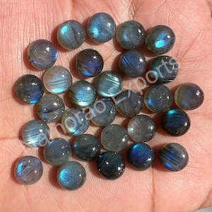 May include: A collection of 30 round, iridescent labradorite cabochons. The stones are a mix of grey, blue, and green with a shimmery, iridescent finish.