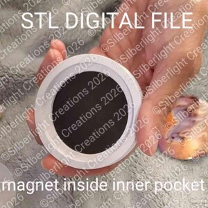 May include: A circular white plastic frame with a dark gray circular center, labeled STL DIGITAL FILE at the top and magnet inside inner pocket at the bottom, designed for 3D printing projects.