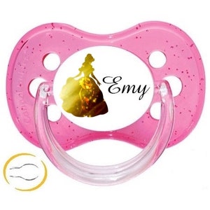 Op de afbeelding: Een roze fopspeen met een doorzichtige handgreep en een ronde, met glitter bezaaide schild. Het midden toont een silhouet van een prinses en de naam "Emy" in cursief. De fopspeen heeft een klein logo.