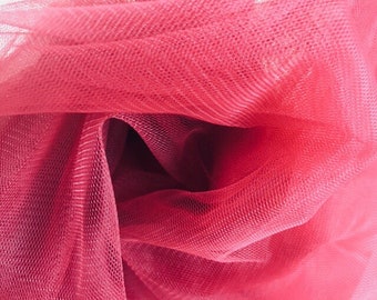 May include: Close-up of a vibrant pink tulle fabric. The delicate mesh is layered and gathered, creating a soft, textured appearance. The fabric's folds and shadows add depth and dimension to the image.