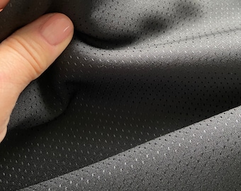 Puede incluir: Primer plano de una tela gris oscuro perforada. El material tiene un brillo sutil y una textura fina y punteada. La tela se sostiene, mostrando su flexibilidad y caída. La imagen resalta el tejido y el color de la tela.