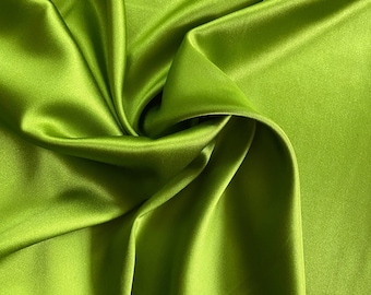 May include: Close-up of a vibrant, lime green satin fabric. The fabric is draped and folded, creating soft shadows and highlights. The smooth, shiny material reflects light, showcasing its luxurious texture. Ideal for apparel, home decor, or craft projects.