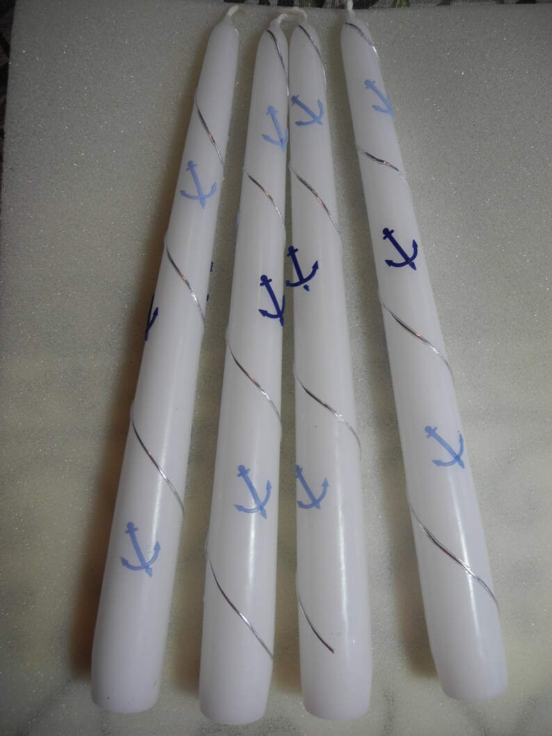 Peut inclure: Quatre bougies chauffe-plat blanches avec des accents argent&eacute;s et bleus. Chaque bougie a un motif d'ancre bleue.