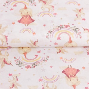 Könnte beinhalten: Ein weißer Stoff mit einem sich wiederholenden Muster aus rosa und gelben Regenbögen, Einhörnern und einem Mädchen, das ein rosa Kleid und eine Krone trägt. Der Hintergrund ist weiß mit kleinen rosa Sternen.