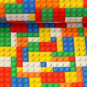 Könnte beinhalten: Ein farbenfroher Stoff mit einem Muster aus ineinandergreifenden Spielzeugbausteinen. Das Design umfasst verschiedene Farben wie Rot, Blau, Grün, Gelb, Orange und Weiß. Die Blöcke sind in einem rasterartigen Muster angeordnet und erzeugen eine verspielte und lebendige Ästhetik.