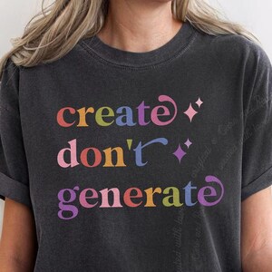Puede incluir: Una camiseta de manga corta en color gris carbón con el texto multicolor "create don't generate" impreso en la parte delantera. El diseño incluye pequeños iconos de estrellas de cuatro puntas en rosa y morado, con letras redondeadas.