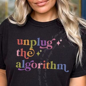 Peut inclure: Un t-shirt noir à manches courtes avec le texte multicolore "unplug the algorithm" imprimé sur le devant. Le motif comprend de petits accents en forme d'étoile et un texte cursif subtil et pâle intégré à l'arrière-plan du graphique.