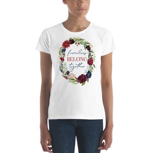 May include: White t-shirt with a floral wreath design and the text "families BELONG together" in red and blue.