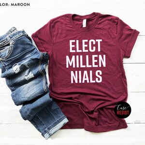 May include: A maroon t-shirt with white text that reads "Elect Millenials".