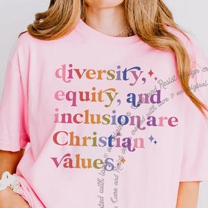 May include: Pink t-shirt with the text "diversity, equity, and inclusion are Christian values" in rainbow colors.