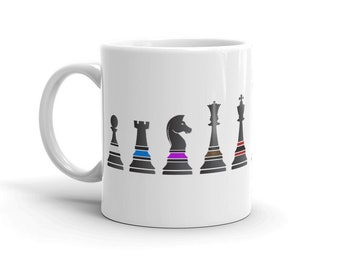 Puede incluir: Taza de cerámica blanca con una silueta negra de piezas de ajedrez en el lateral. Las piezas están dispuestas en línea desde el peón hasta el rey, con cada pieza teniendo una banda de color diferente alrededor de la base.