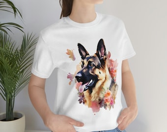 Puede incluir: Camiseta blanca con una ilustración de acuarela de un pastor alemán con flores rosas y naranjas.
