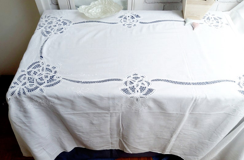 Puede incluir: Mantel blanco con delicados dise&ntilde;os florales bordados. El mantel tiene un patr&oacute;n de encaje con detalles intrincados.