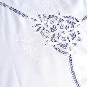 Puede incluir: Tela de algod&oacute;n blanca con delicado bordado de encaje blanco. El encaje presenta un dise&ntilde;o floral con detalles intrincados.