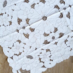 May include: White embroidered tablecloth with a floral design. The tablecloth is made of delicate fabric and features intricate stitching.