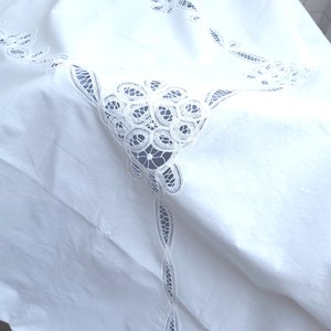 Puede incluir: Mantel blanco con bordado de encaje delicado. El encaje presenta un dise&ntilde;o floral con detalles intrincados.