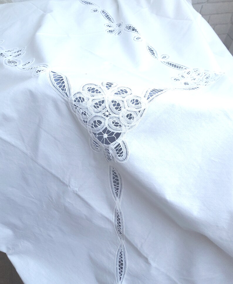 Puede incluir: Mantel blanco con bordado de encaje delicado. El encaje presenta un dise&ntilde;o floral con detalles intrincados.