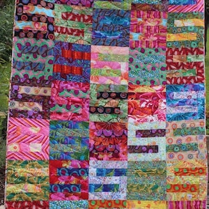 Può includere: Una trapunta patchwork colorata con una varietà di motivi floreali e geometrici in tonalità di rosa, verde, blu, rosso e giallo.